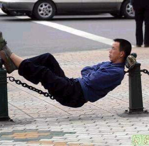 Man is reclining on a chain link fence.