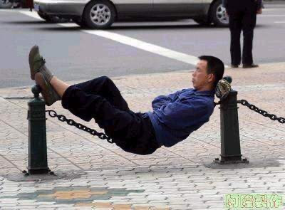 Man is reclining on a chain link fence.