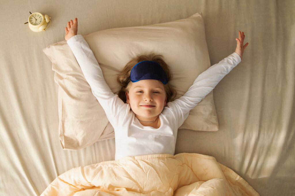 young girl stretches in bed