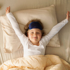 young girl stretches in bed